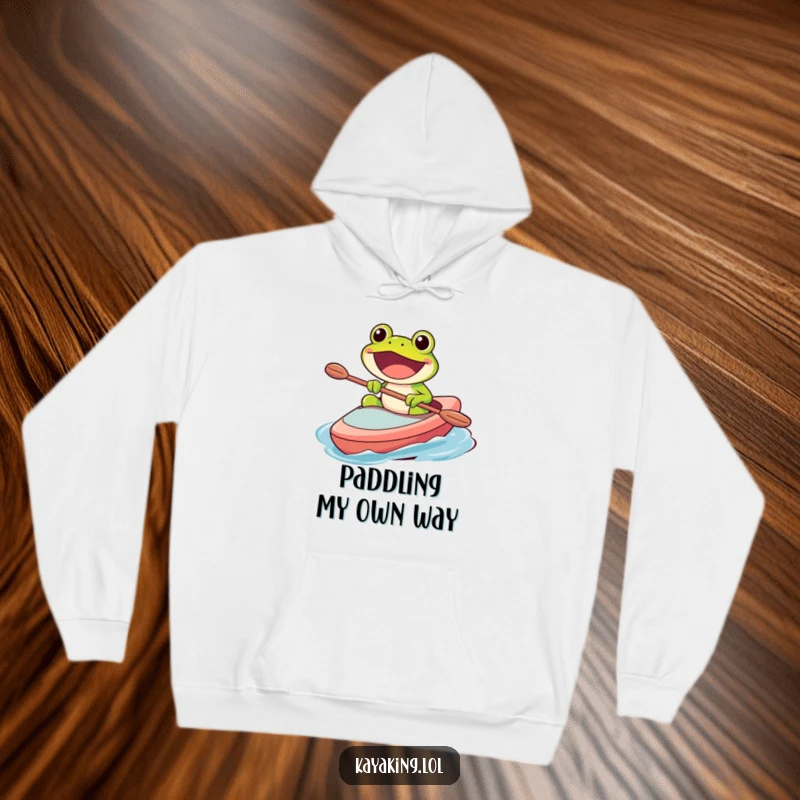 Funny hoodie featuring a happy frog character paddling a kayak with a wide, excited grin, ready for any adventure.