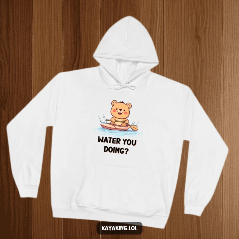 Funny happy bear in a kayak, splashing water with a paddle, depicted on a cozy hoodie, perfect for outdoor enthusiasts.